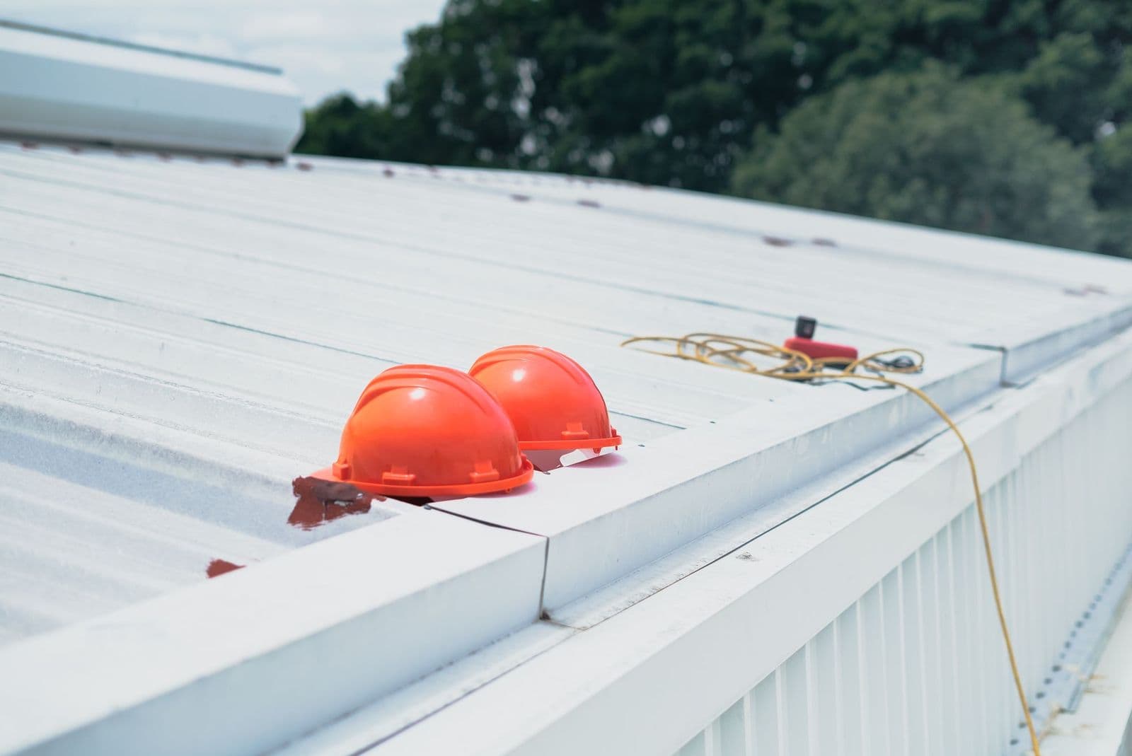 Two hard hats resting on the metal roof of an industrial building