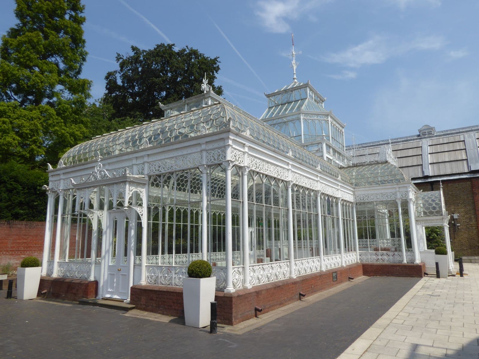 A white-framed glazed conservatory with a glass roof on a brick base