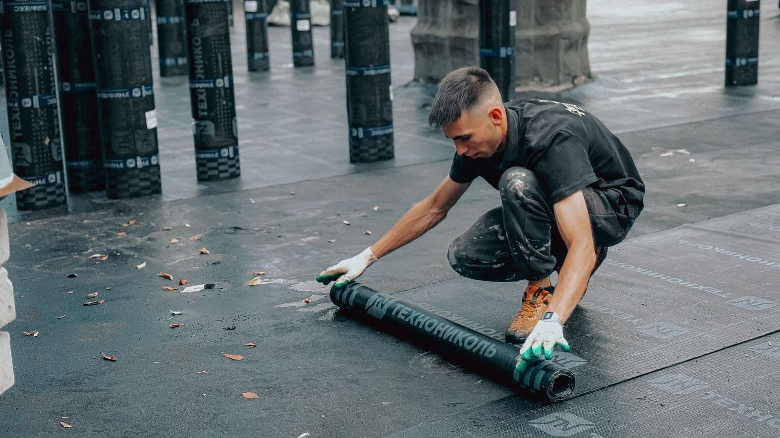 Roofer rolling out a waterproof membrane on a flat roof