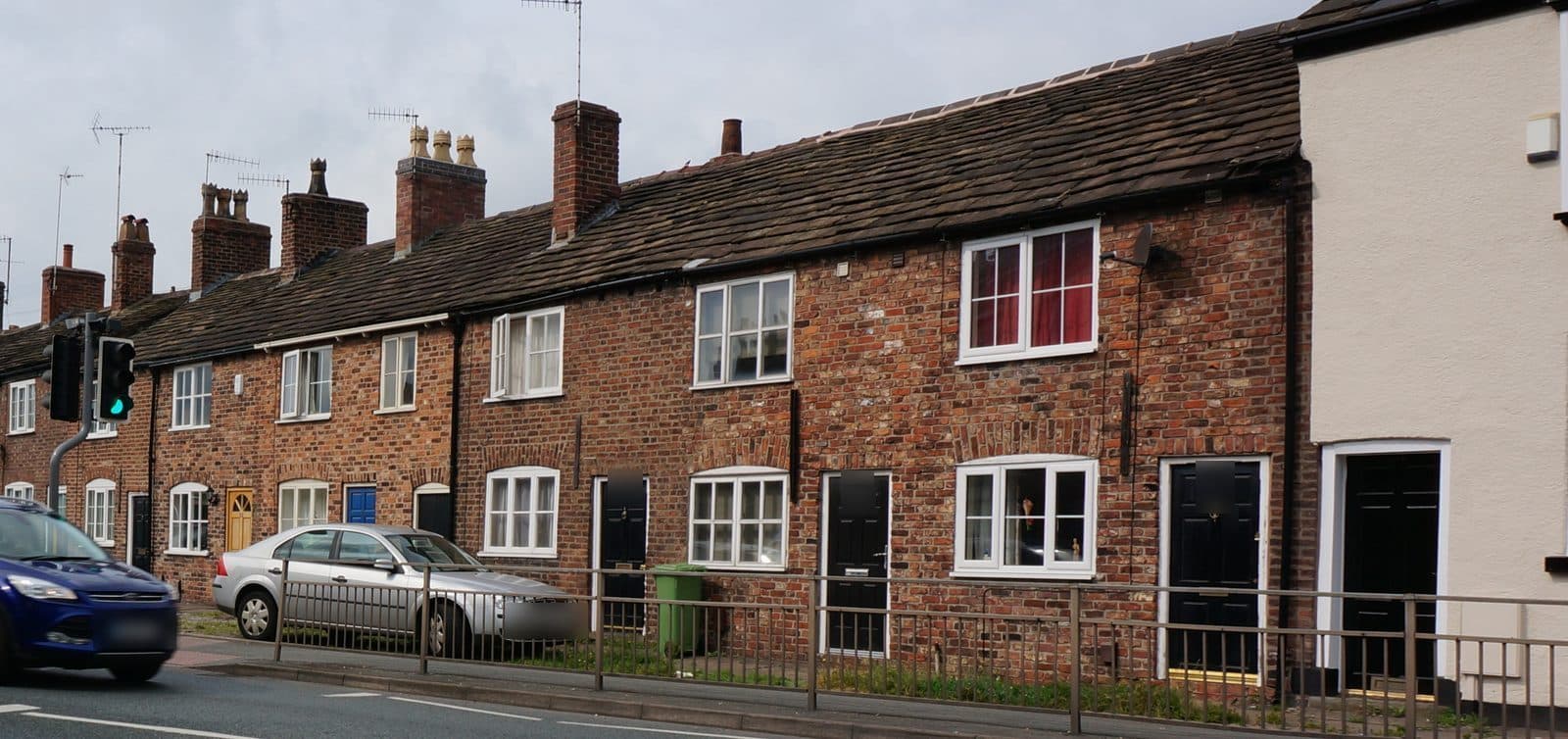 Brick terraced cottages on the A523 in Macclesfield with stone slate roofs and tall chimney stacks