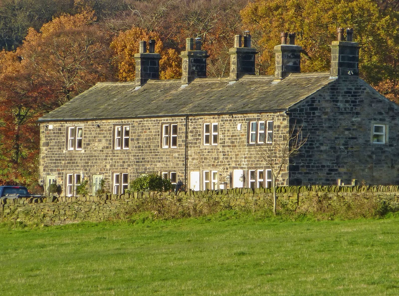 Row of Pennine stone cottages with heavy stone slate roofs and chimneys