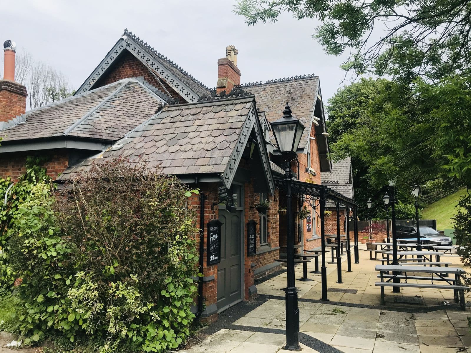 Victorian brick former station building with slate roofs in Cheadle, now a pub