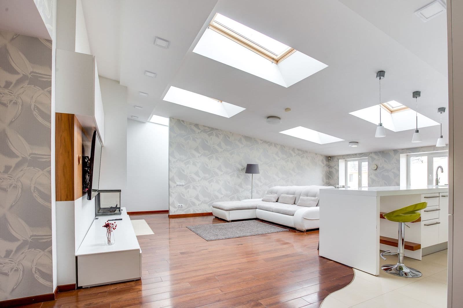 Loft living room lit by several roof windows set into a sloping ceiling